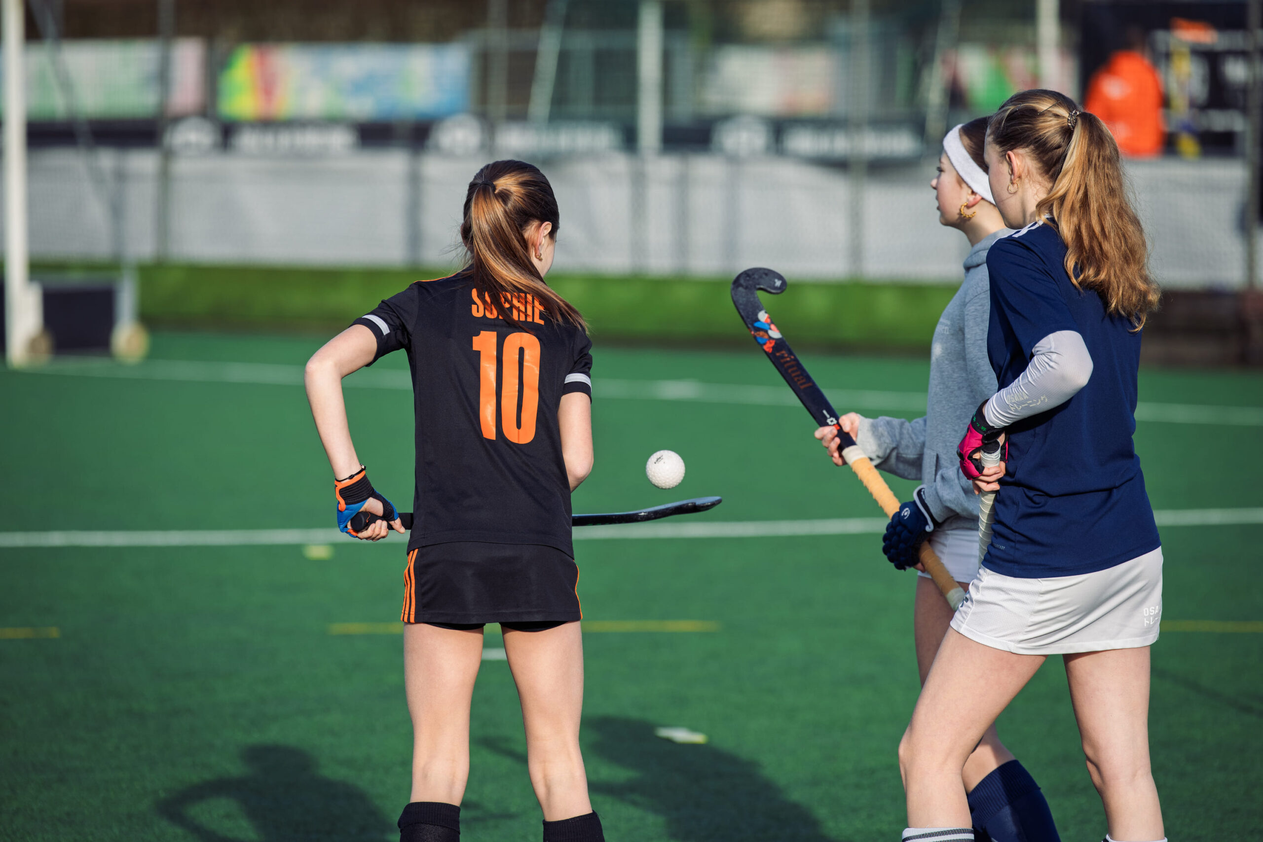 Jonge hockeyspelers in actie tijdens een ProHockey hockekamp op een groen veld, geconcentreerd spelend met hockeyballen en sticks.