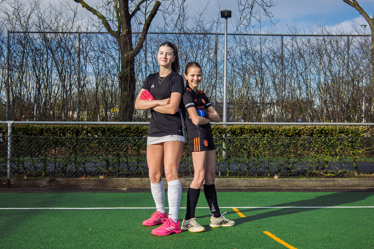 Twee jonge hockeyspelers op een veld in sportieve kleding, deel van ProHockey hockekampen.
