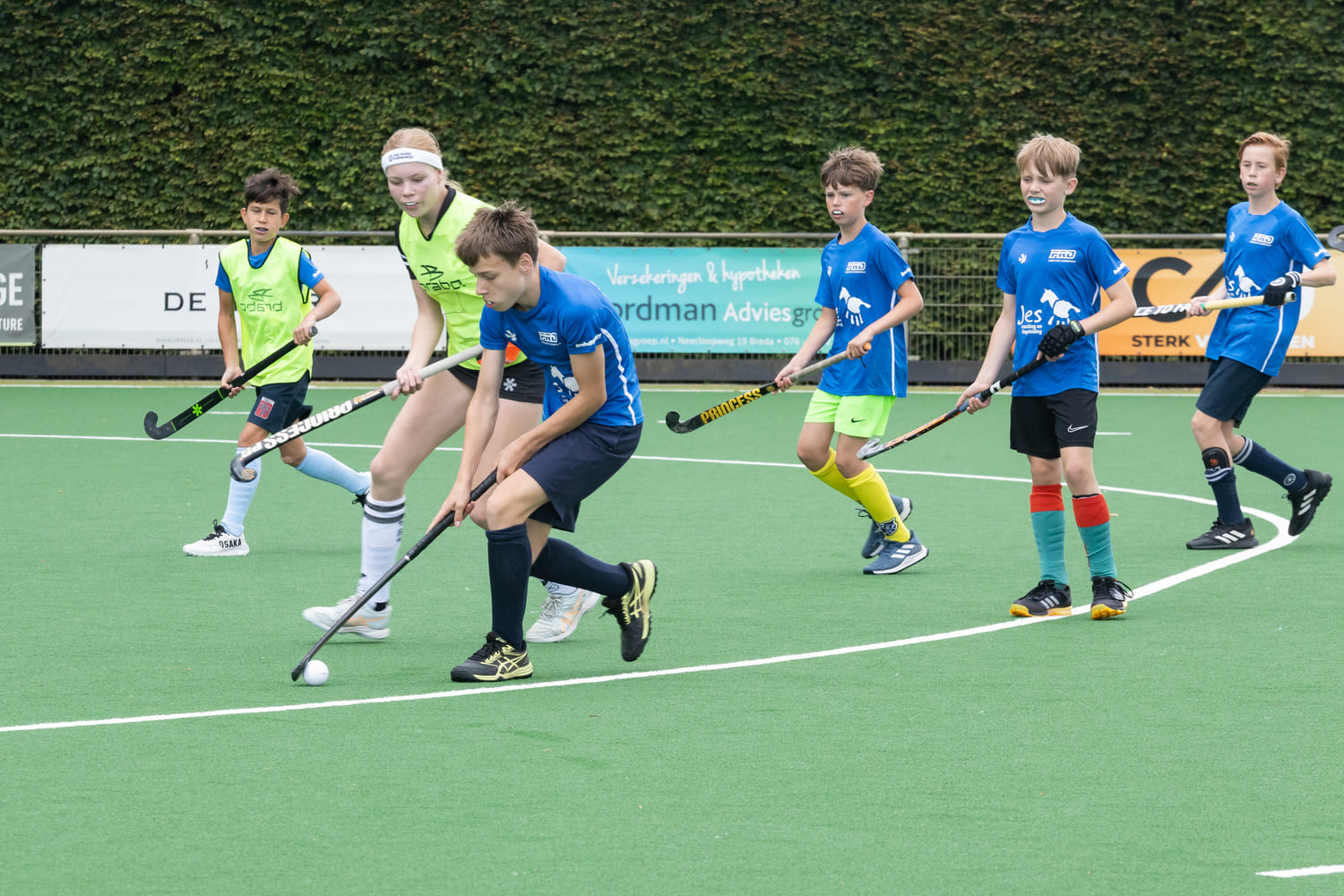 Jonge spelers tijdens een hockeywedstrijd op het ProHockey zomerkamp bij hockeyclub Prinsenbeek, actief op een groen veld.