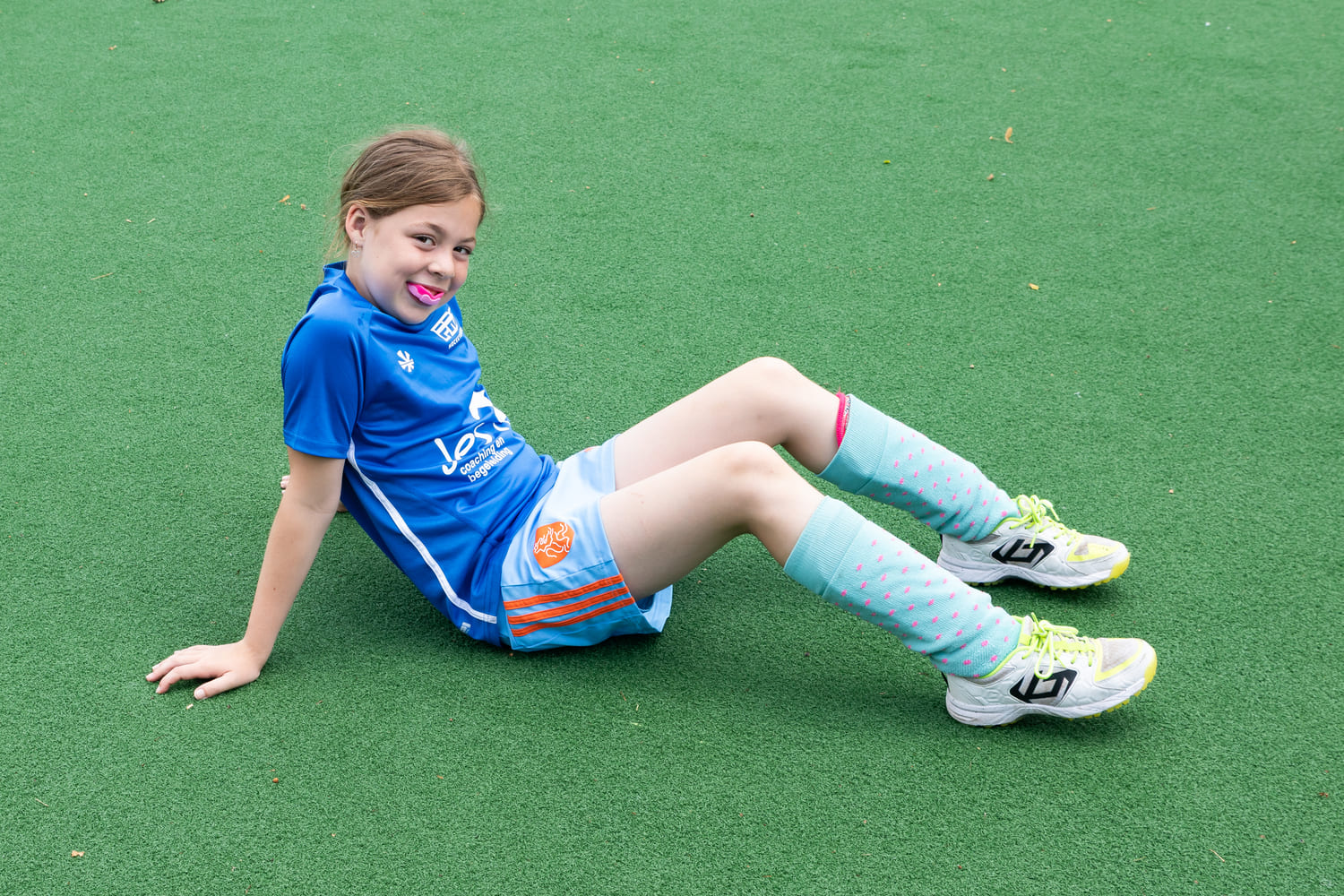 Kind in blauwe hockeyoutfit bij ProHockey zomerkamp op kunstgrasveld in Prinsenbeek.